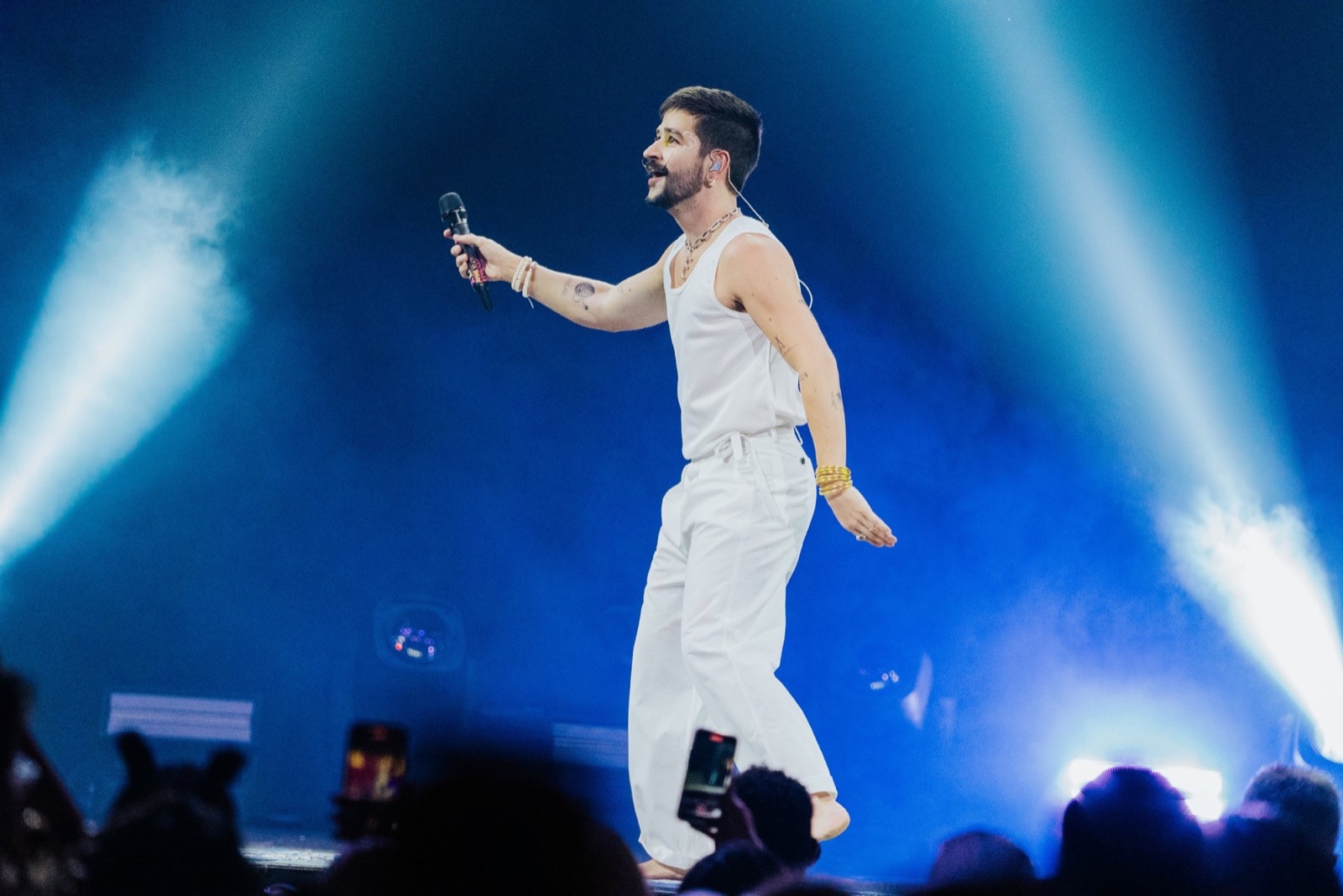 Camilo singing under blue stage light