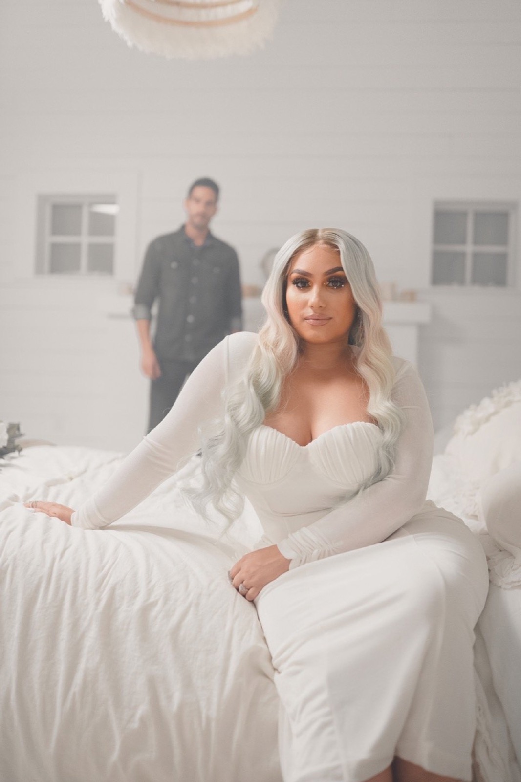 Music video still, couple in a white bedroom