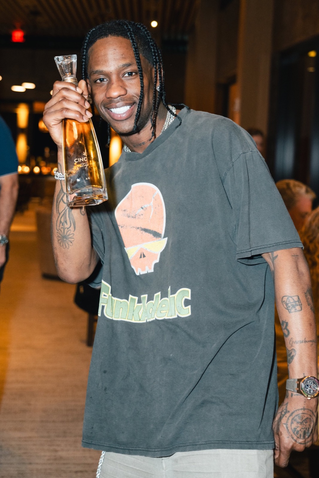 Musician grinning with a bottle at a rooftop party
