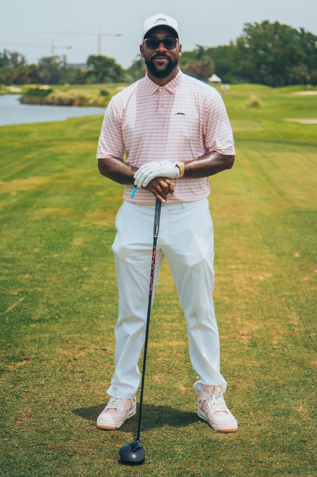 Golfer in white posing with a driver on the fairway