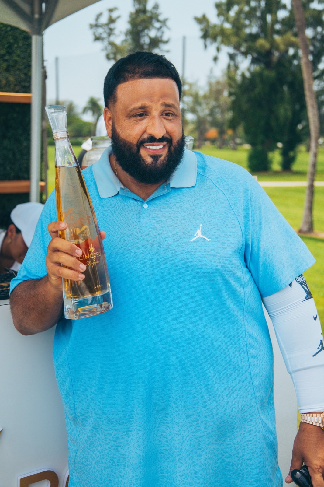 Golfer in a light blue polo holding a bottle on the course