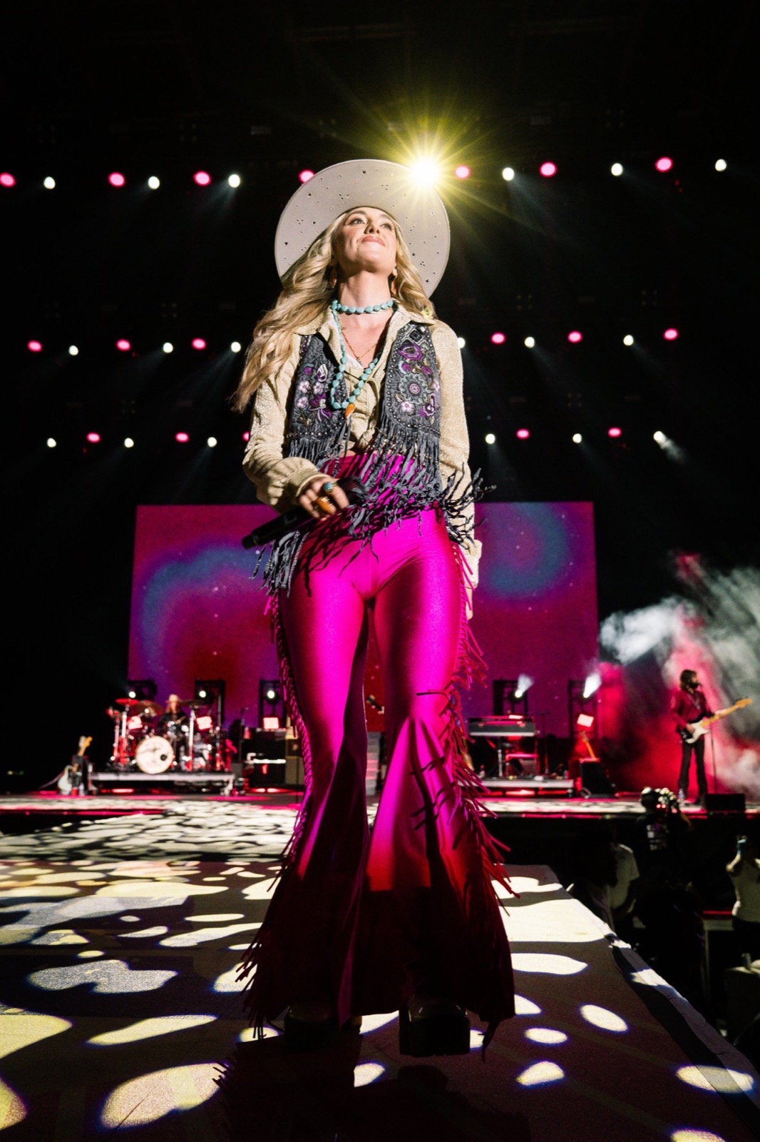 Country singer in a hat and pink pants on a lit stage