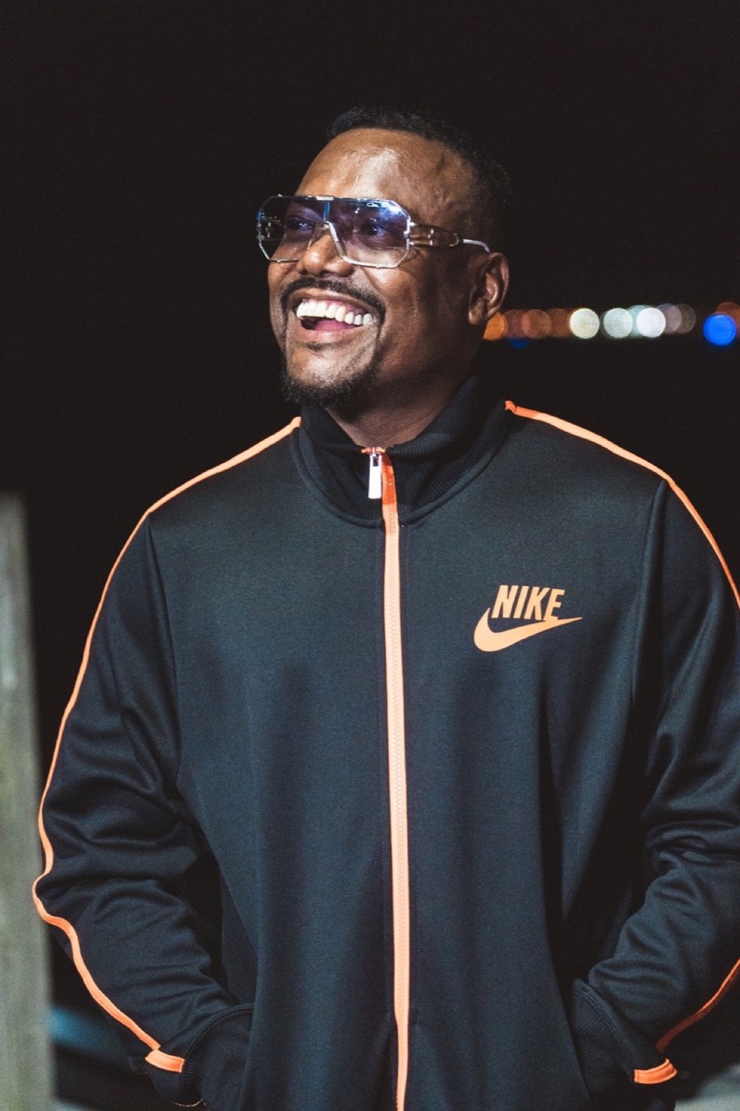 Portrait in a black track jacket against a dark background