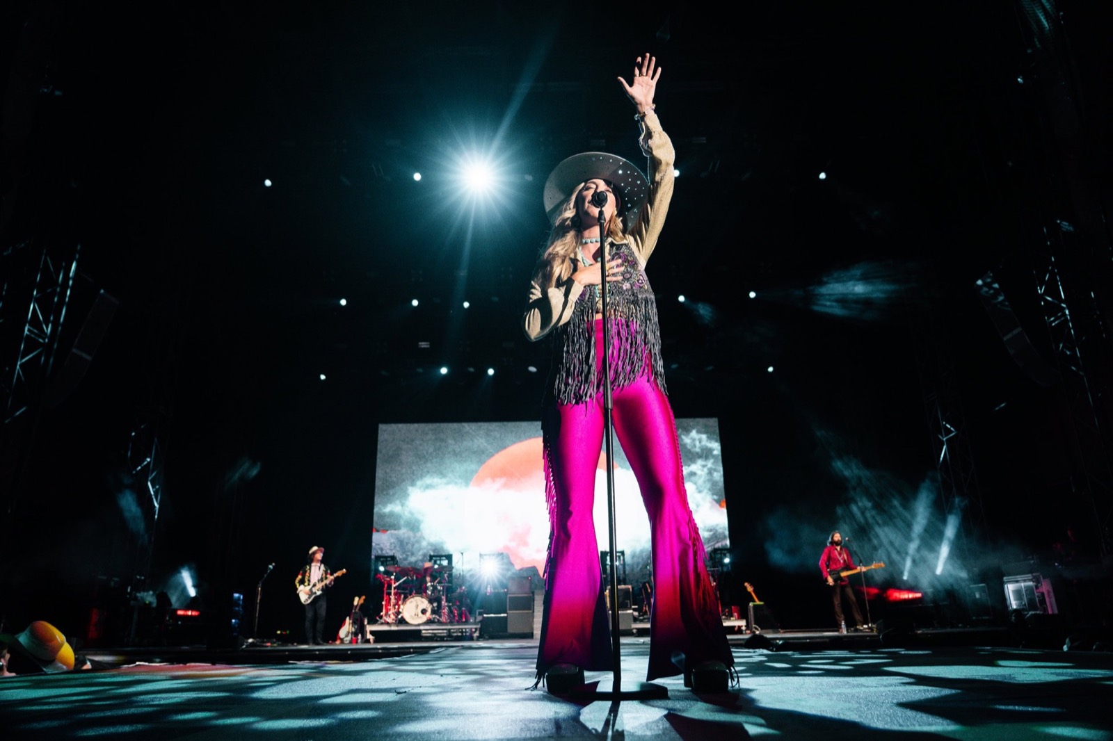 Singer in pink under a wide stage spotlight
