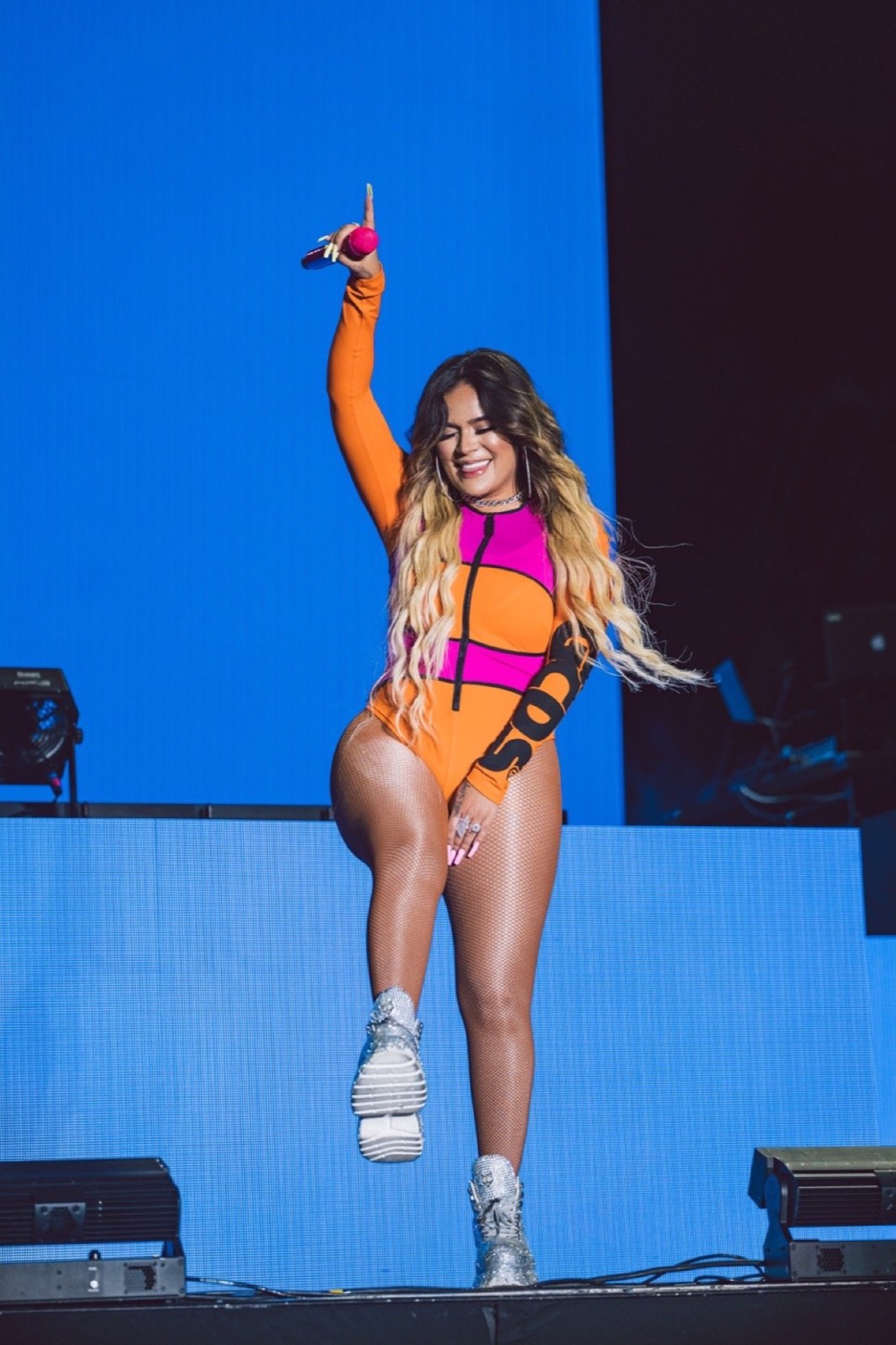Performer in orange against a blue stage wash