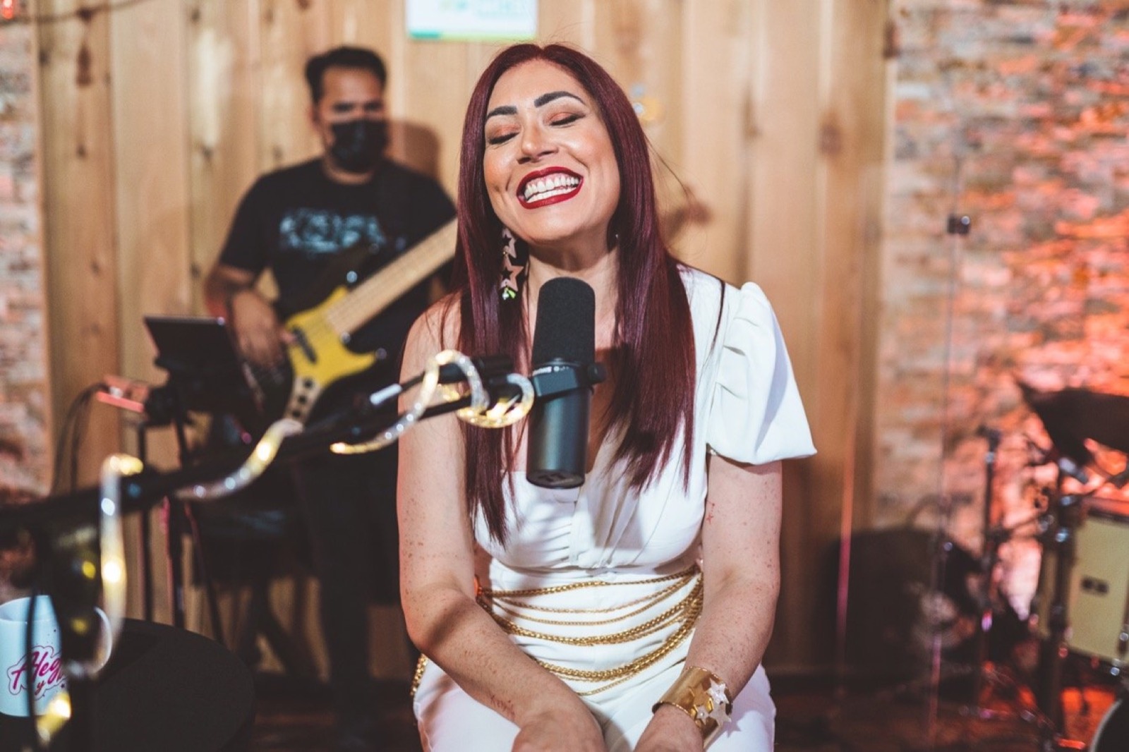 Singer in white at a live session with a guitarist behind
