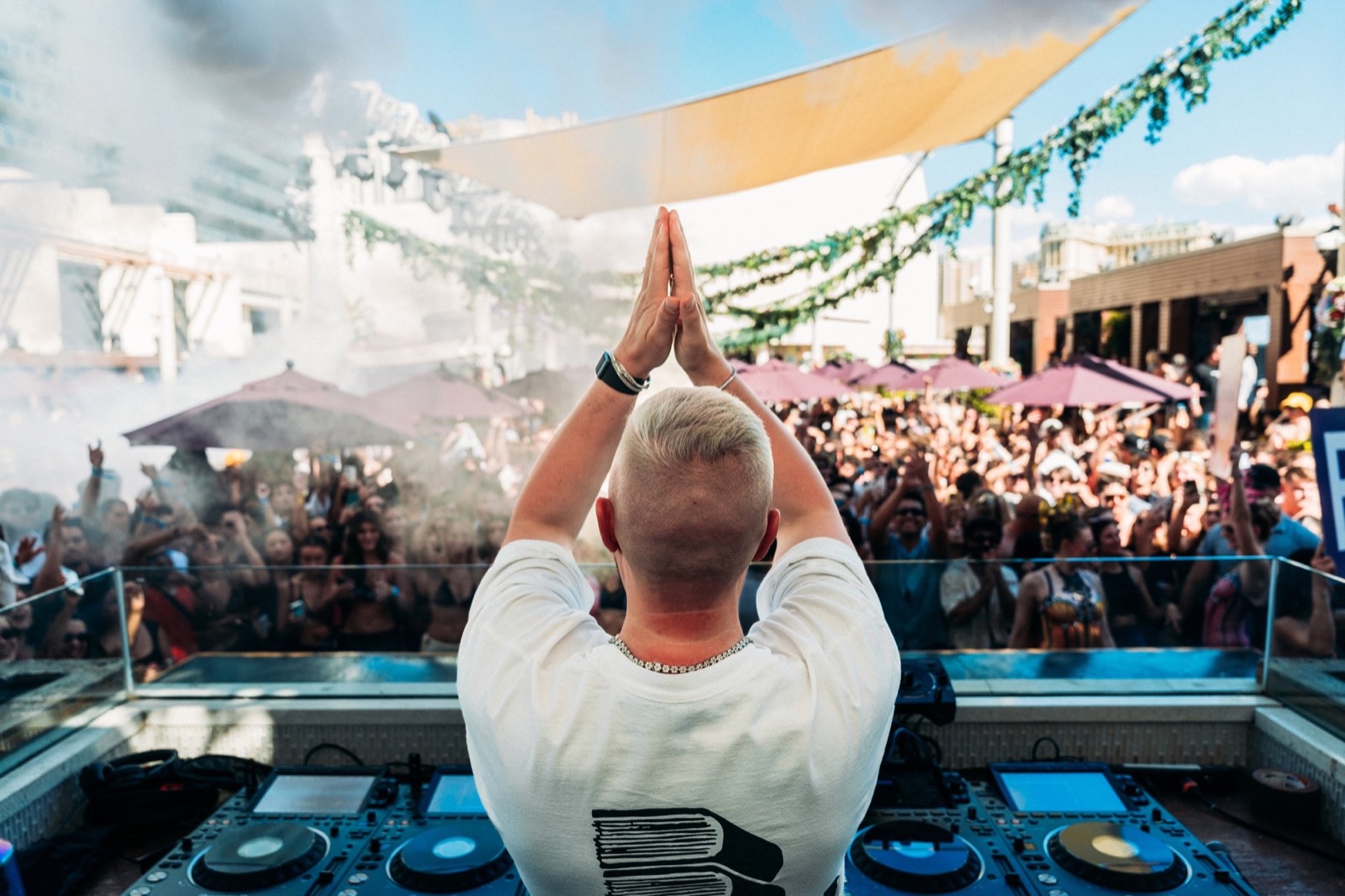 DJ clasping hands over the booth at a day party